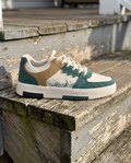 Men's green lace-up fashion sneaker, clean and pristine, on a wooden porch step in morning light