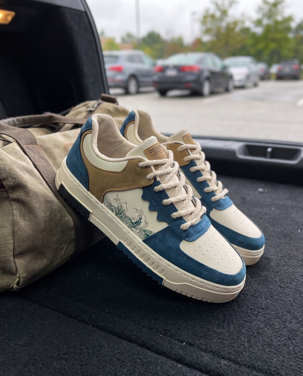 Men's blue lace-up fashion sneaker resting on a car trunk with a gym bag